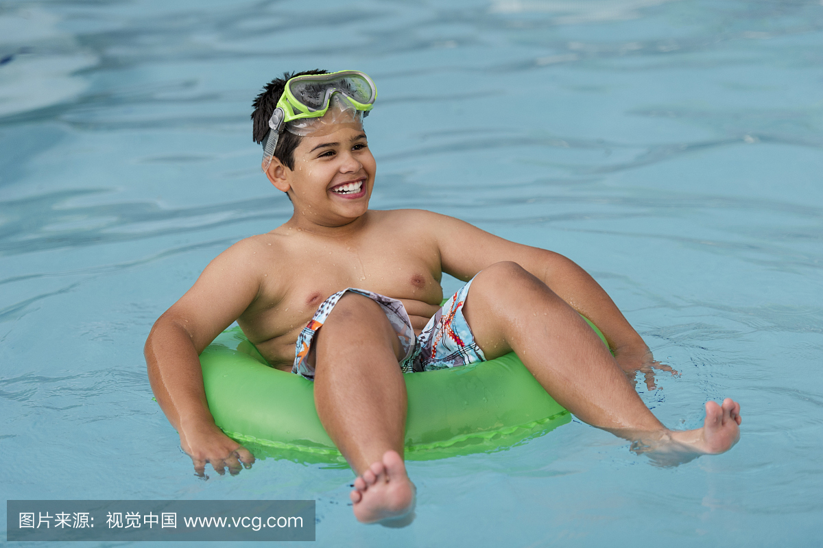 超级男孩玩在一个游泳池与环浮动