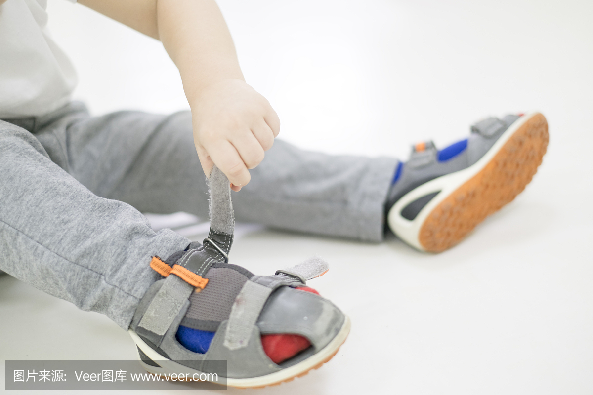 小孩子试图穿上他的鞋子。男婴与手中的鞋子。