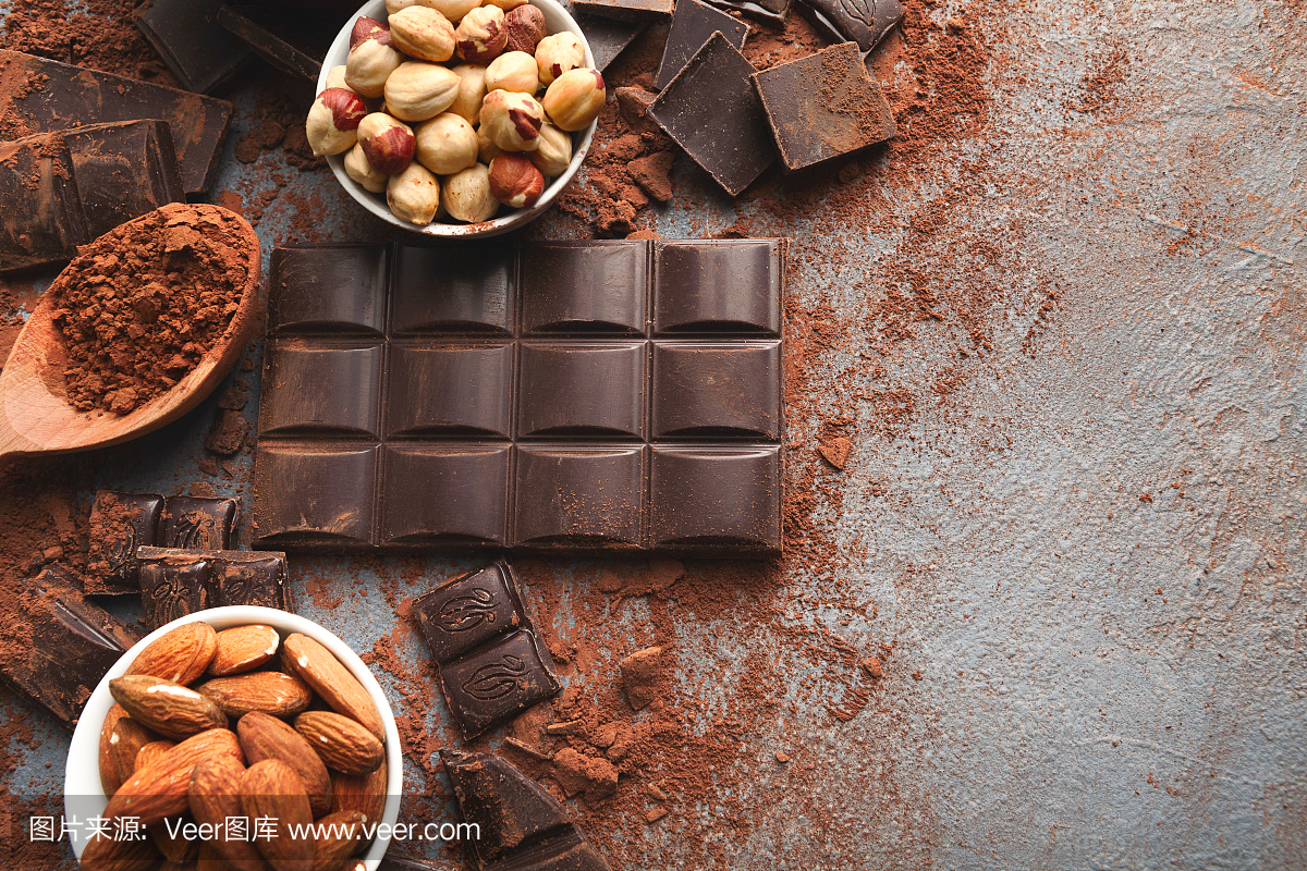 被击碎的巧克力块片和可可粉在灰色的背景上