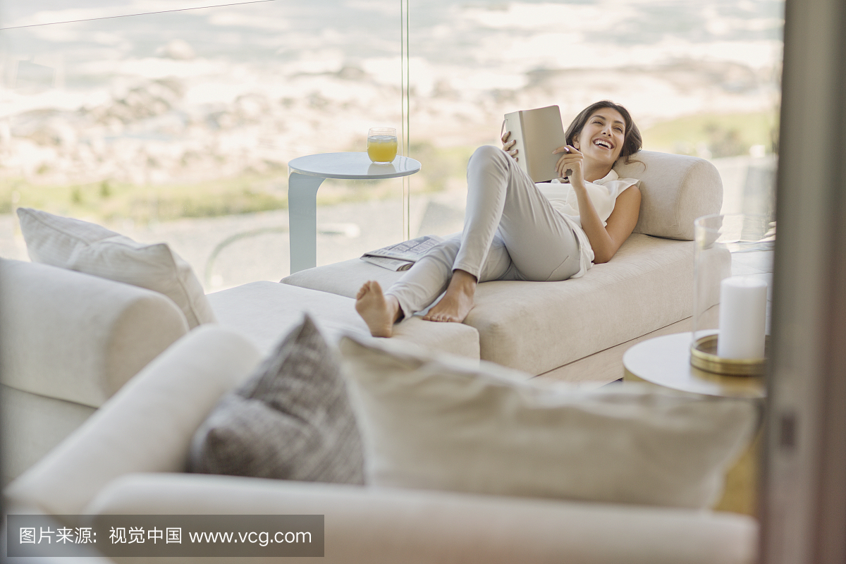 躺在躺椅上的微笑的女人阅读书放松