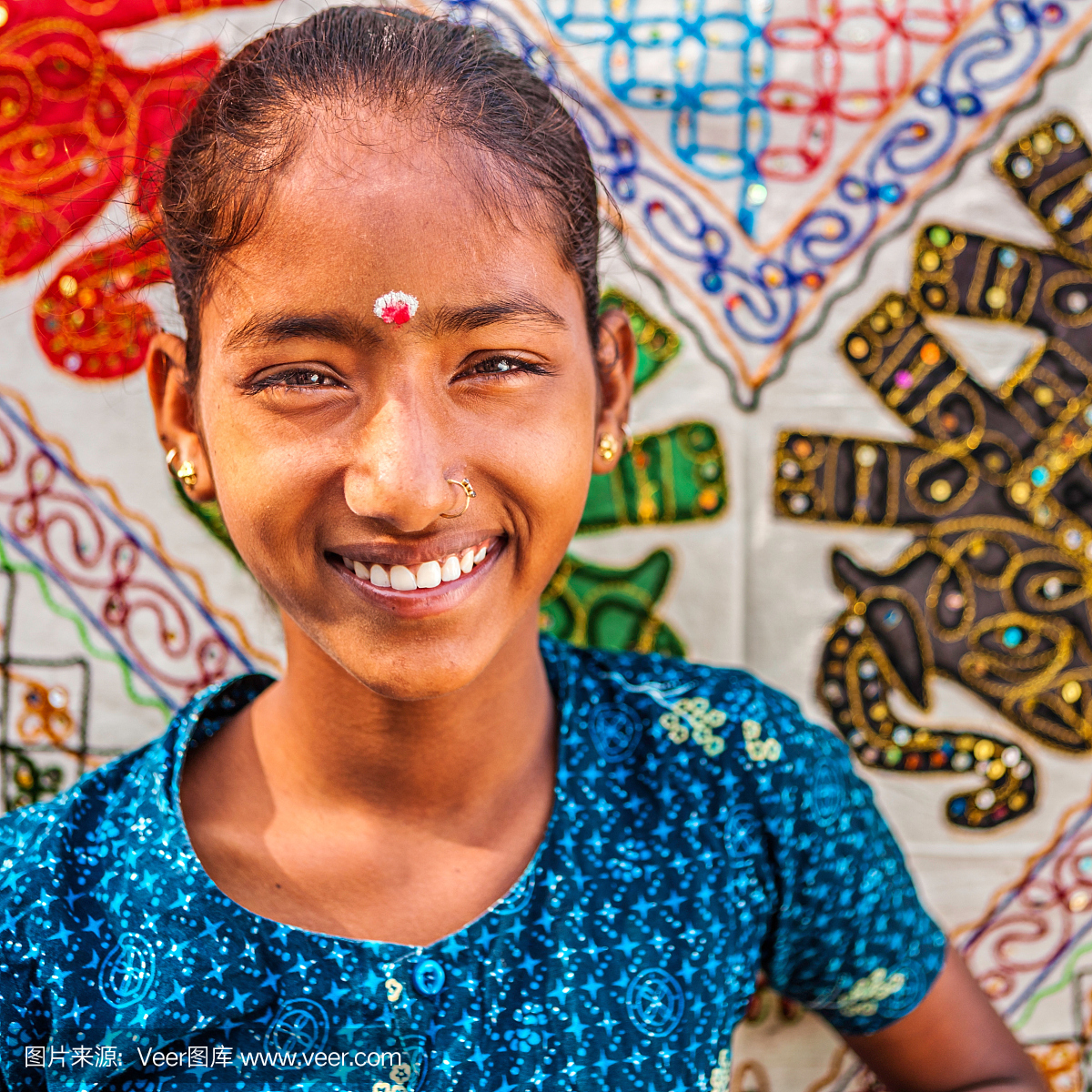 年轻的印度女孩卖五颜六色的刺绣地毯