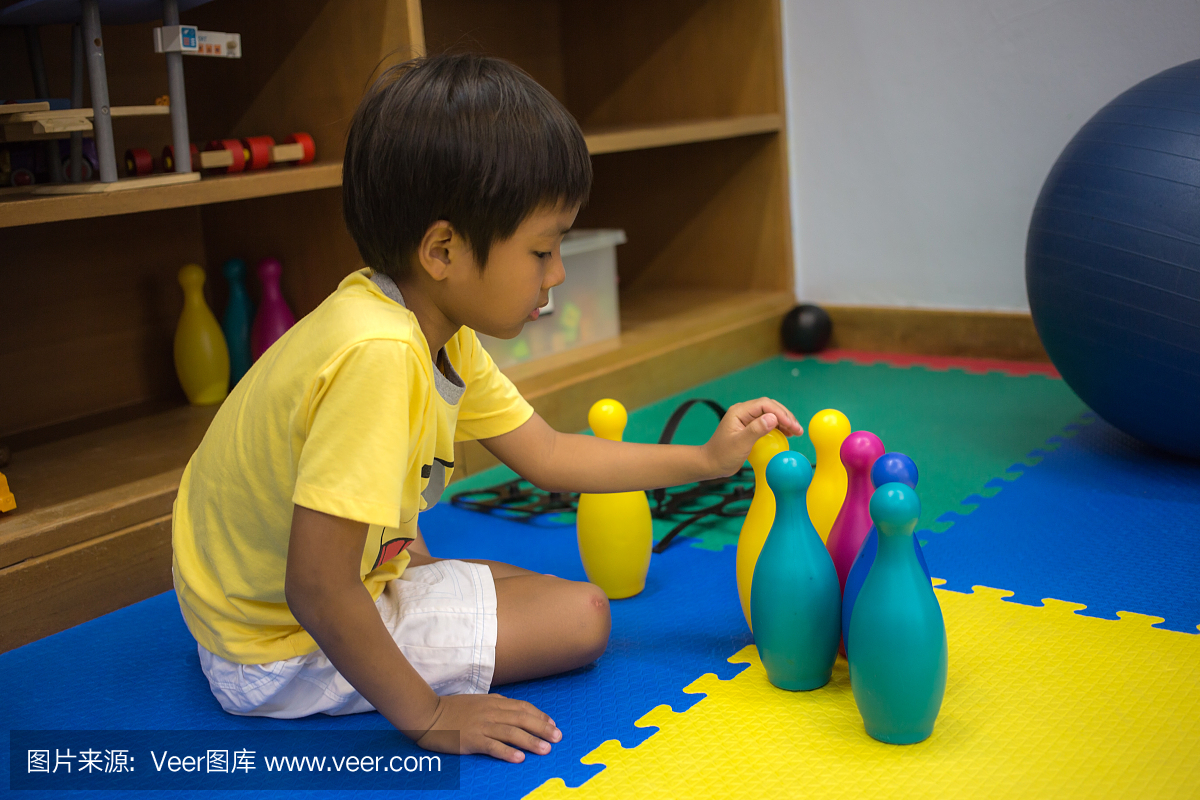 单身8岁的亚洲男孩在娱乐室玩彩色玩具
