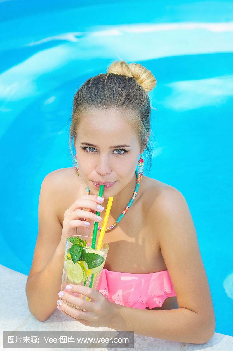 在游泳池喝柠檬水的年轻女子