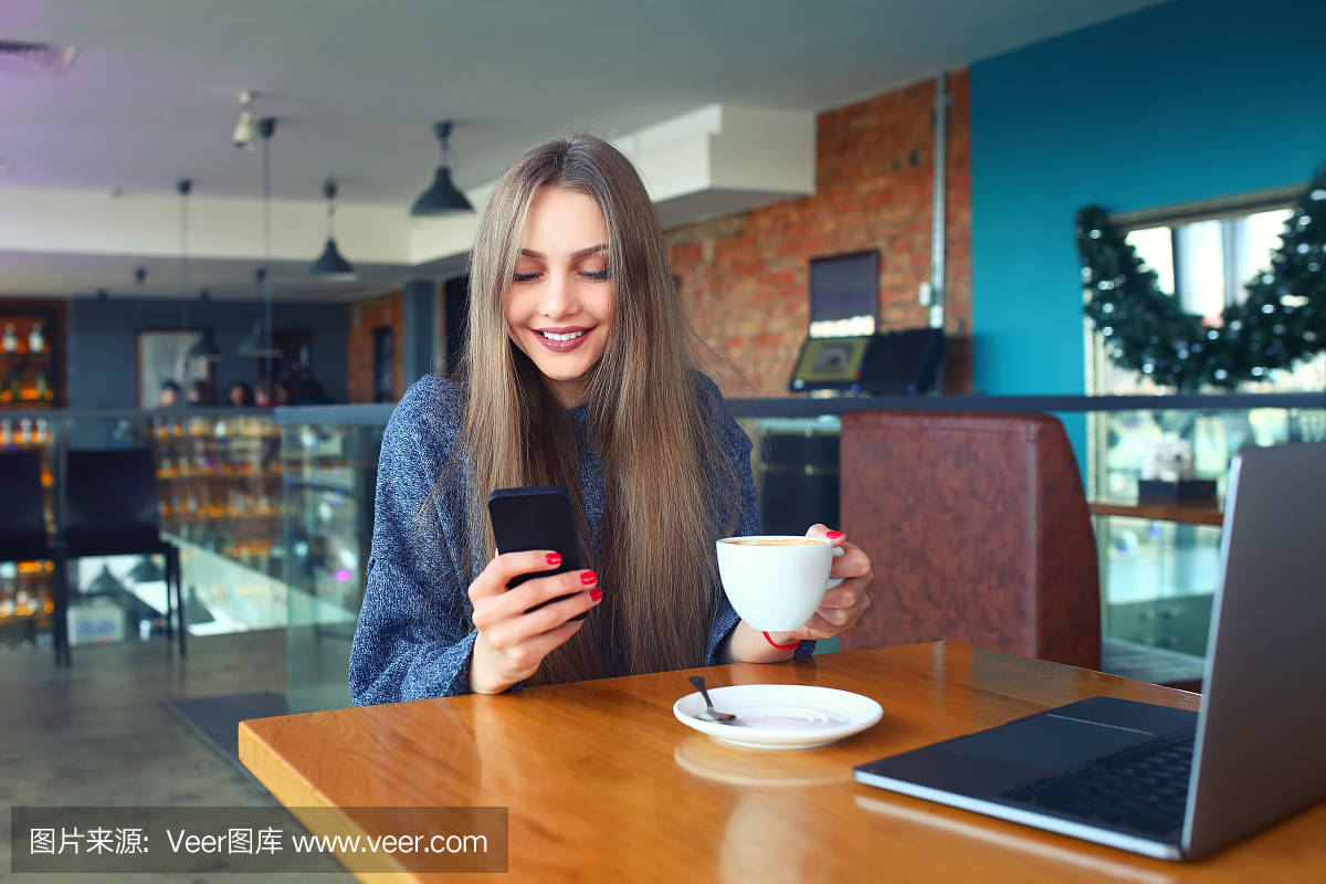女人在一家咖啡馆的智能手机上键入文本消息。