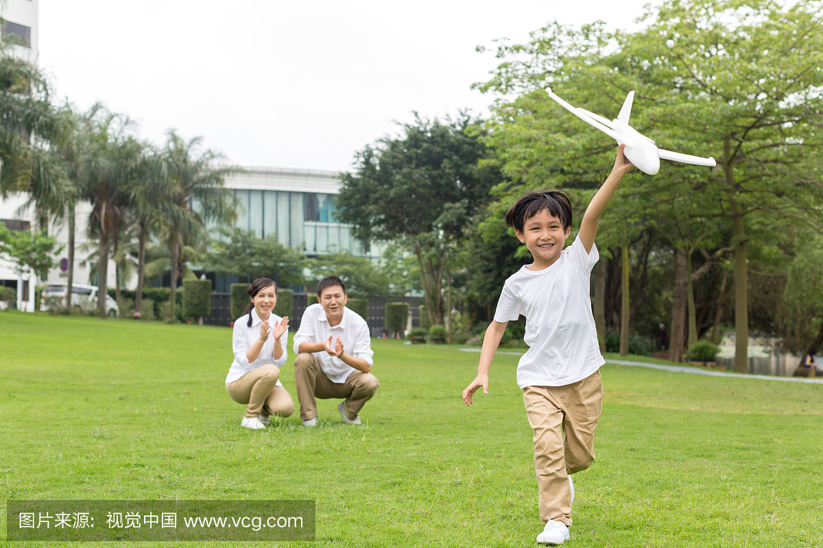 快乐的一家人在公园玩飞机模型