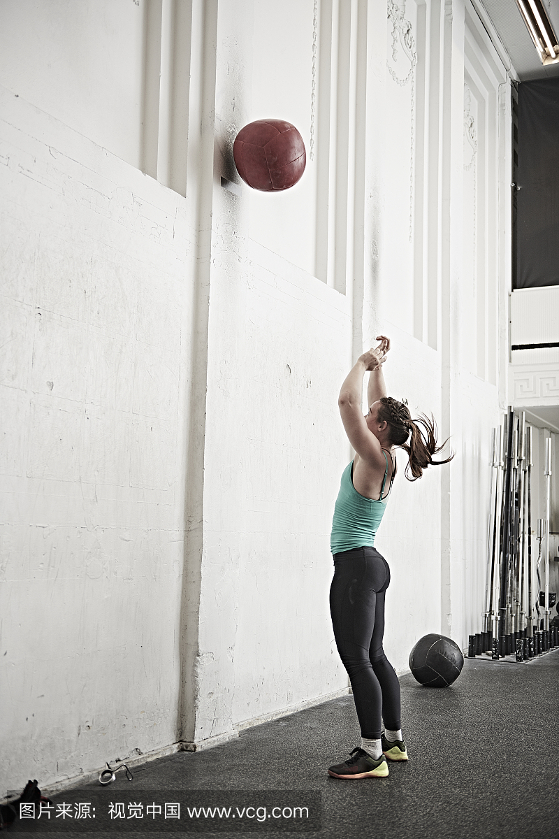 女子投掷健身球在墙上交叉训练健身房