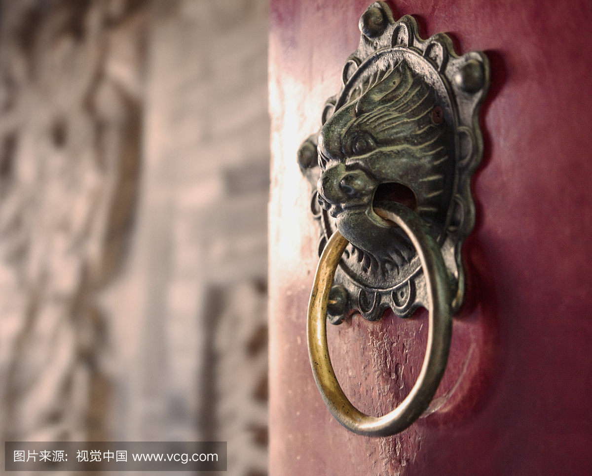 Close-up of ornate gold door knocker on red do