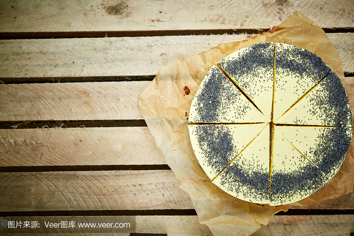 切片慕斯蛋糕与黄釉和罂粟种子在木制的背景上
