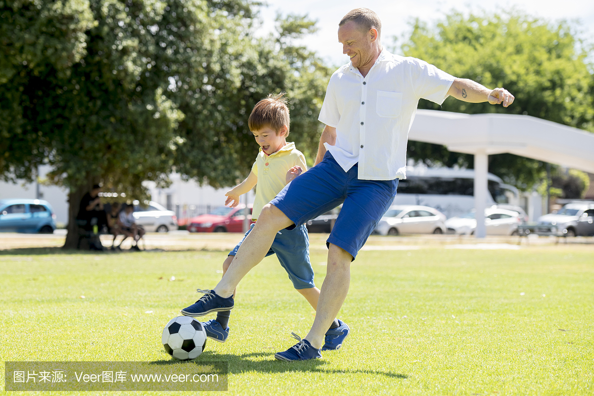 年轻快乐的父亲和兴奋7或8岁的儿子一起踢足