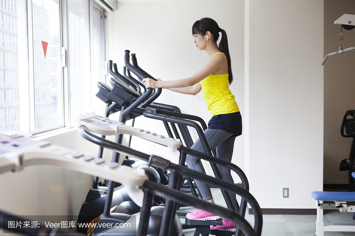 一个女人在听音乐时在健身房锻炼。