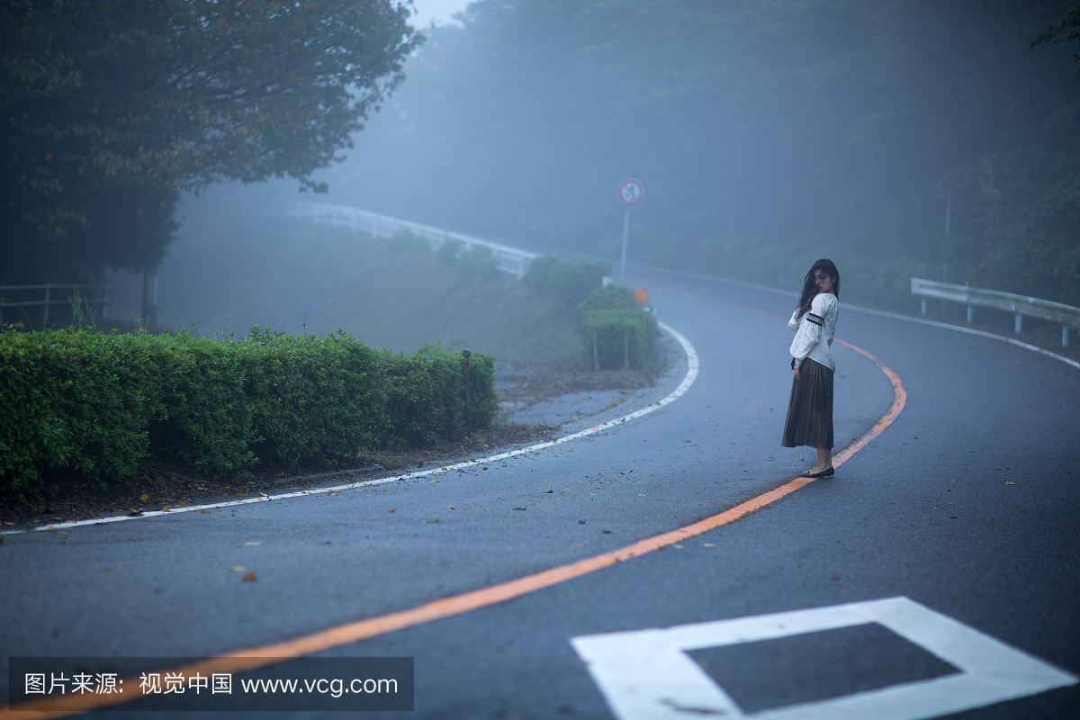一个女人站在雾路上