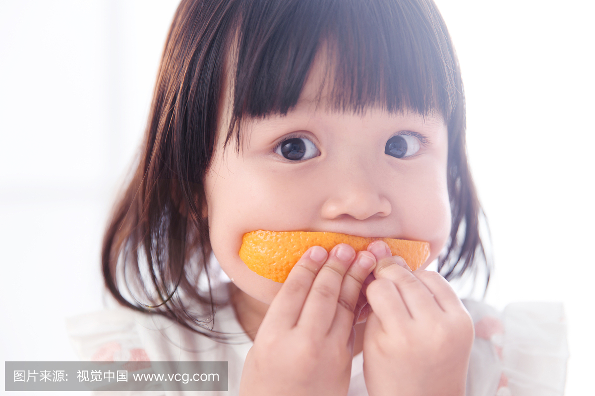 可爱的小女孩在吃橙子