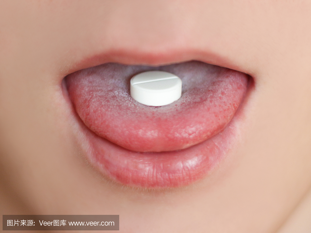 一个白色的药丸在男性的嘴里的特写镜头。舌头