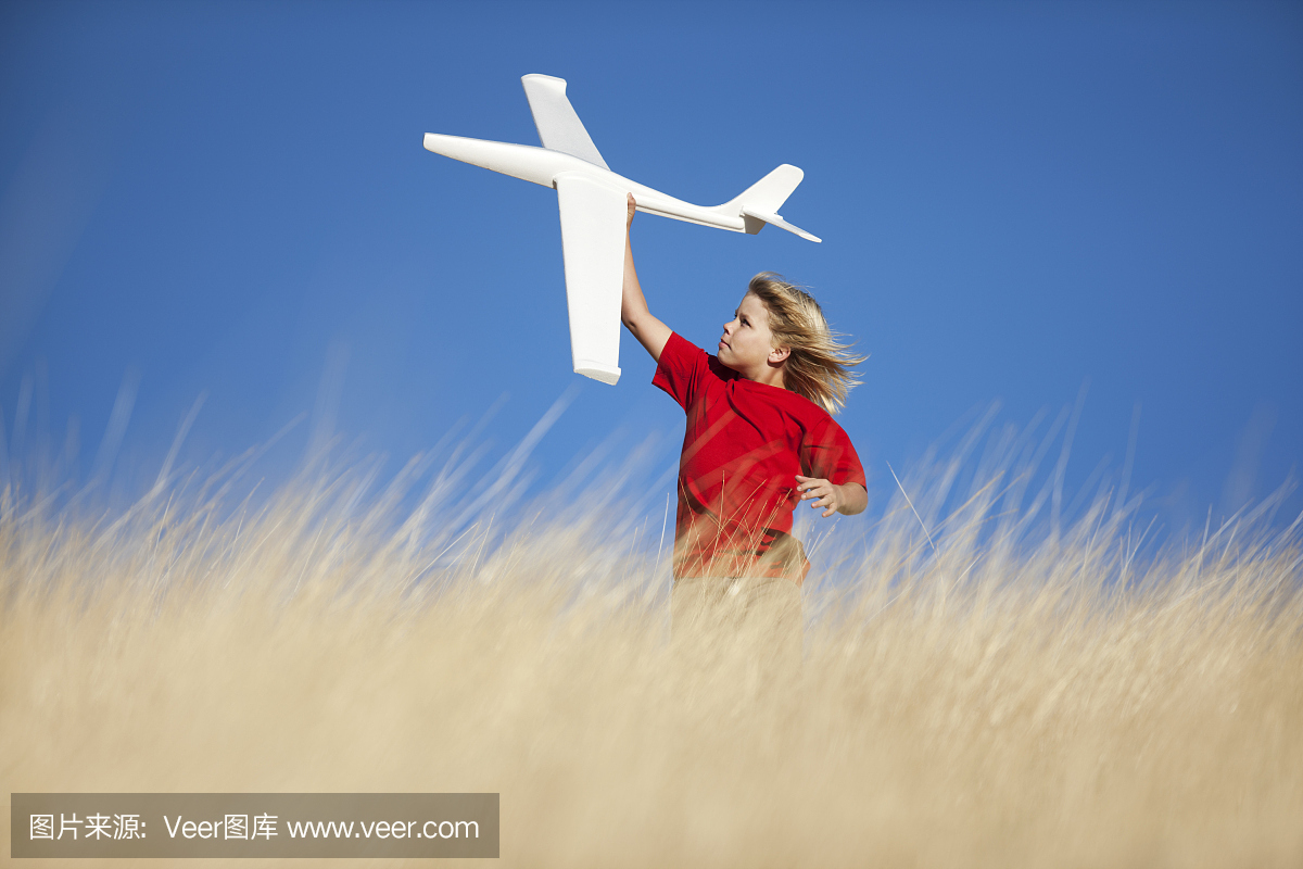 玩玩具滑翔机飞机在场上的年轻男孩