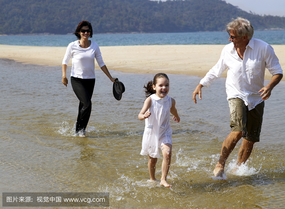 孙女(4-6岁)和在沙滩上跑的祖父母
