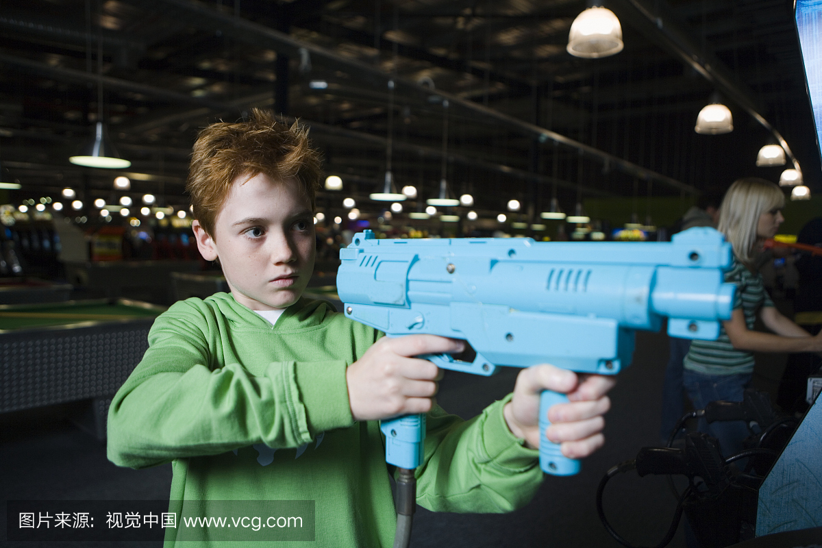 男孩(12-13)与玩具枪在视频街机游戏