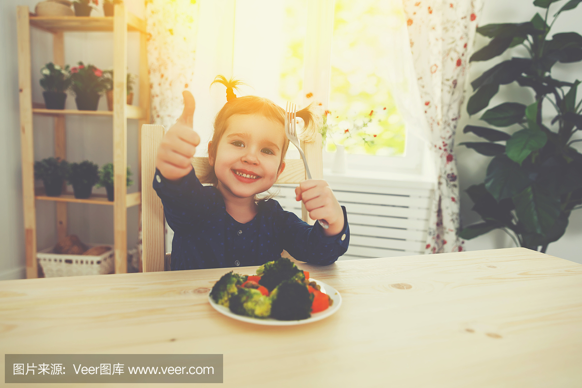 快乐的孩子喜欢吃蔬菜,并竖起大拇指