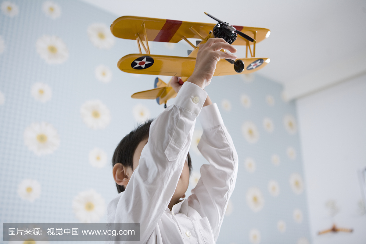 男孩(4-5岁)玩玩具飞机在室内,低角度视图