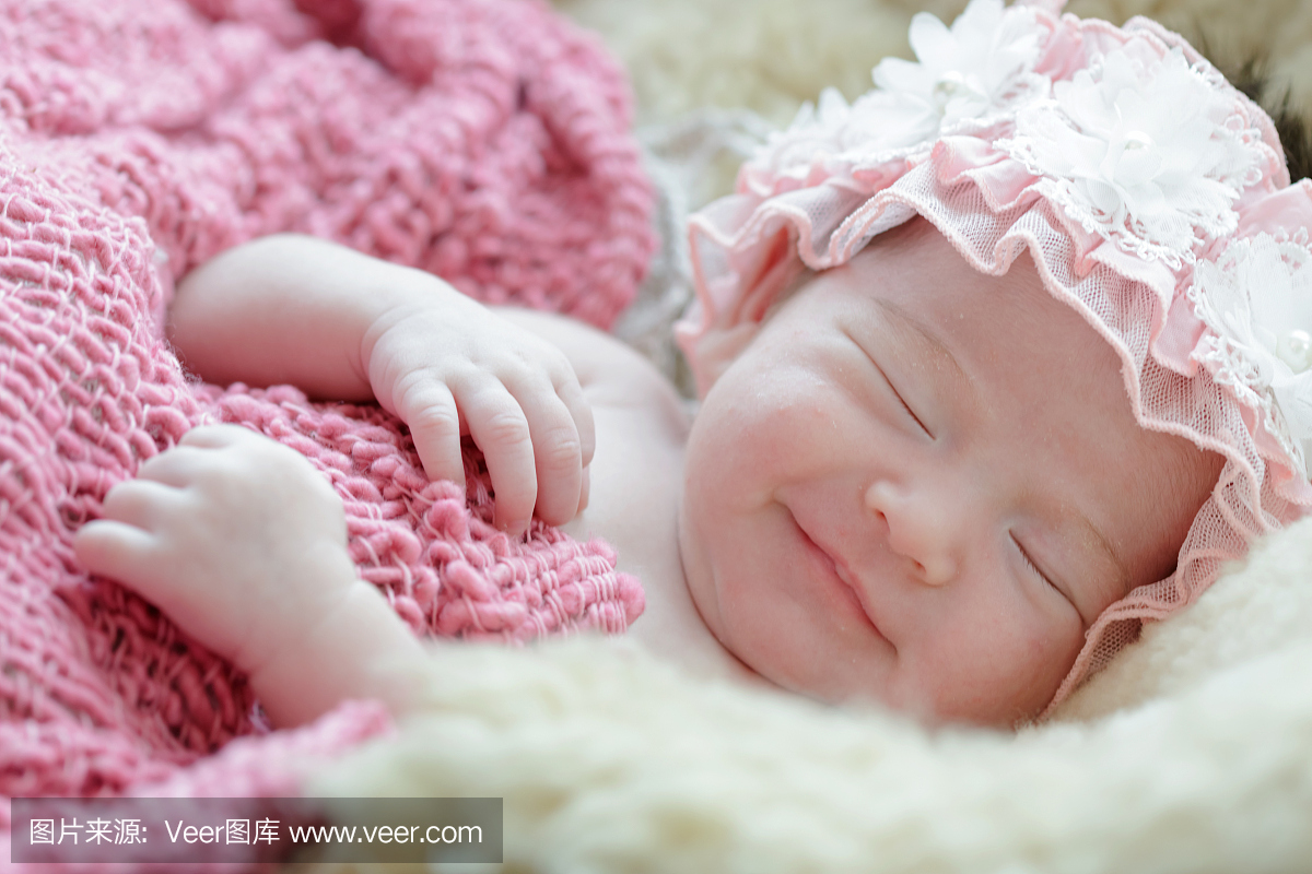 刚出生的婴儿女孩在梦中微笑,初生女婴睡在毛