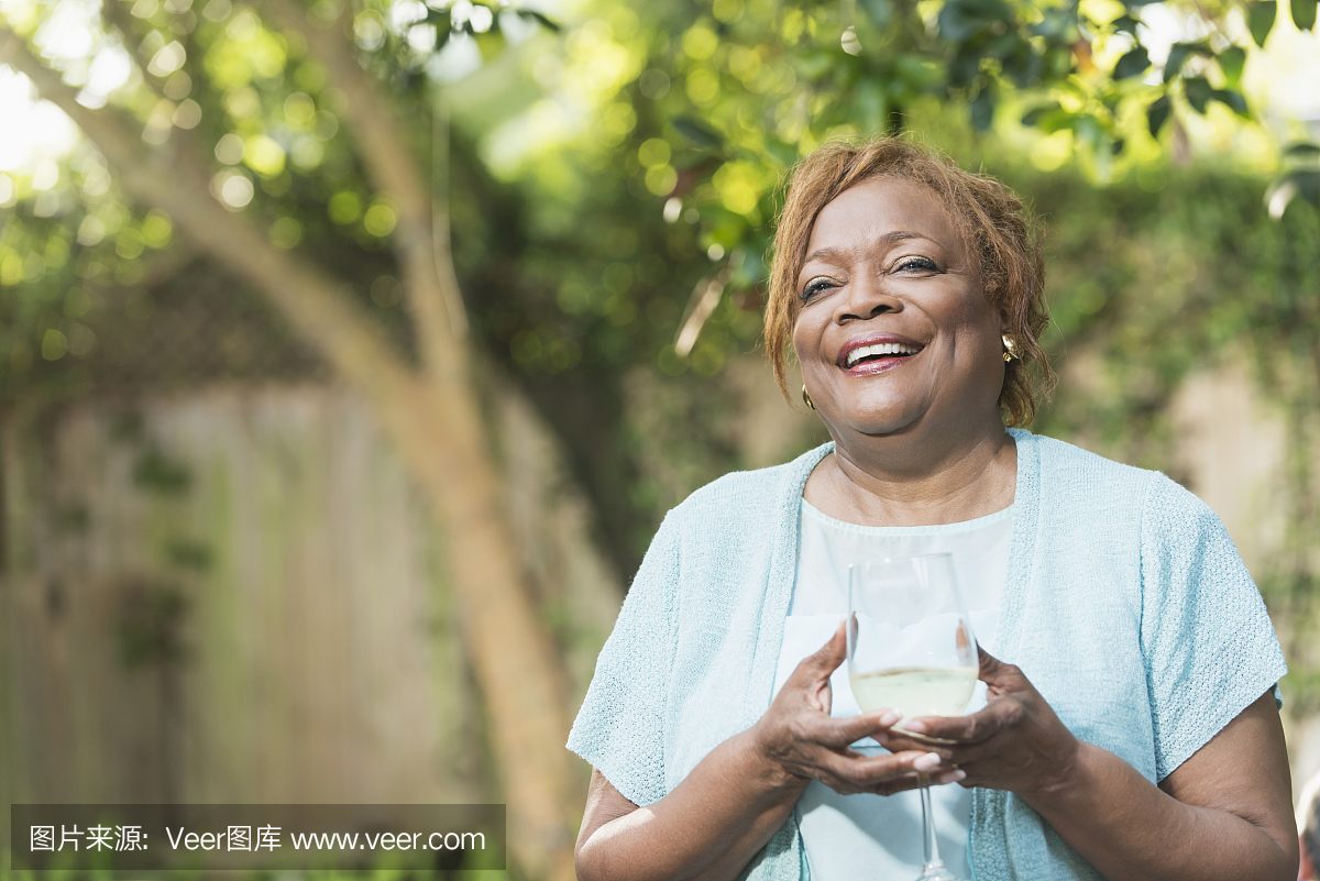 高级非裔美国人的女人与一杯白葡萄酒