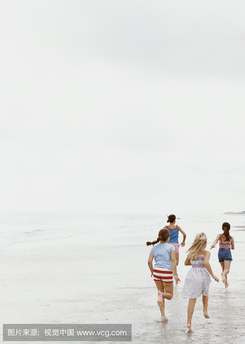 四个女孩(7-12)在海滩上跑步,后视图