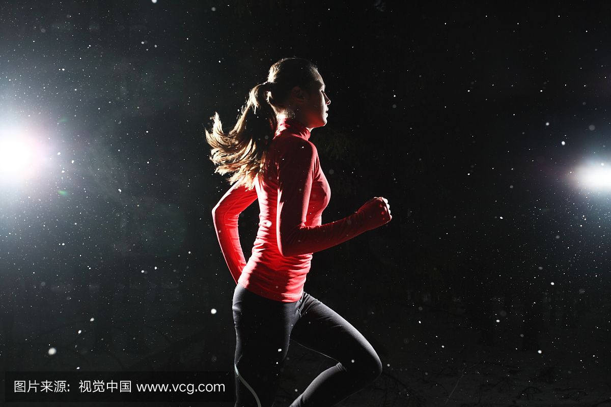 一个晚上跑步的女孩被雪花包围着