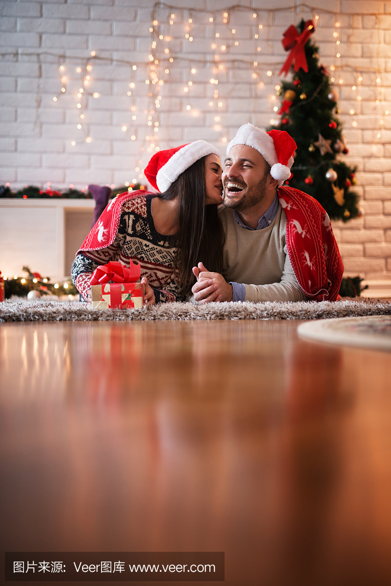 迷人幸福的夫妇,与圣诞老人的帽子躺在红毯子