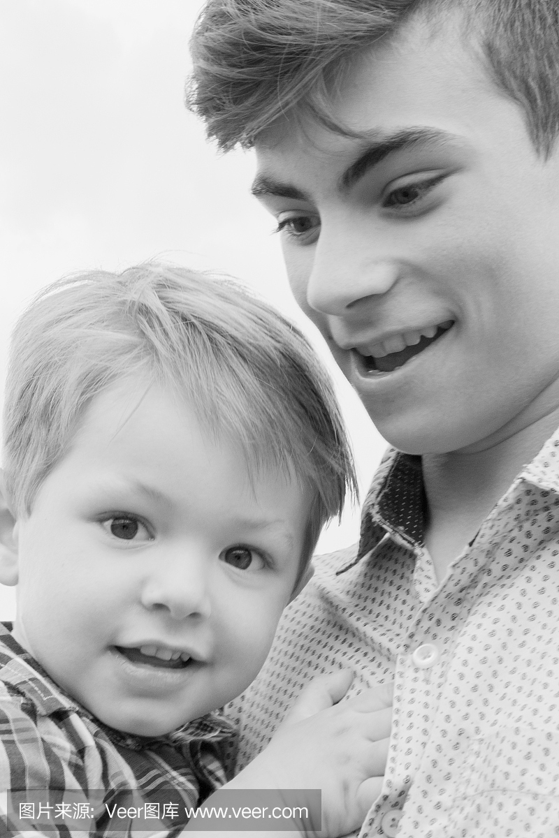 十几岁的男孩与弟弟在怀里走在一个字段中的黑