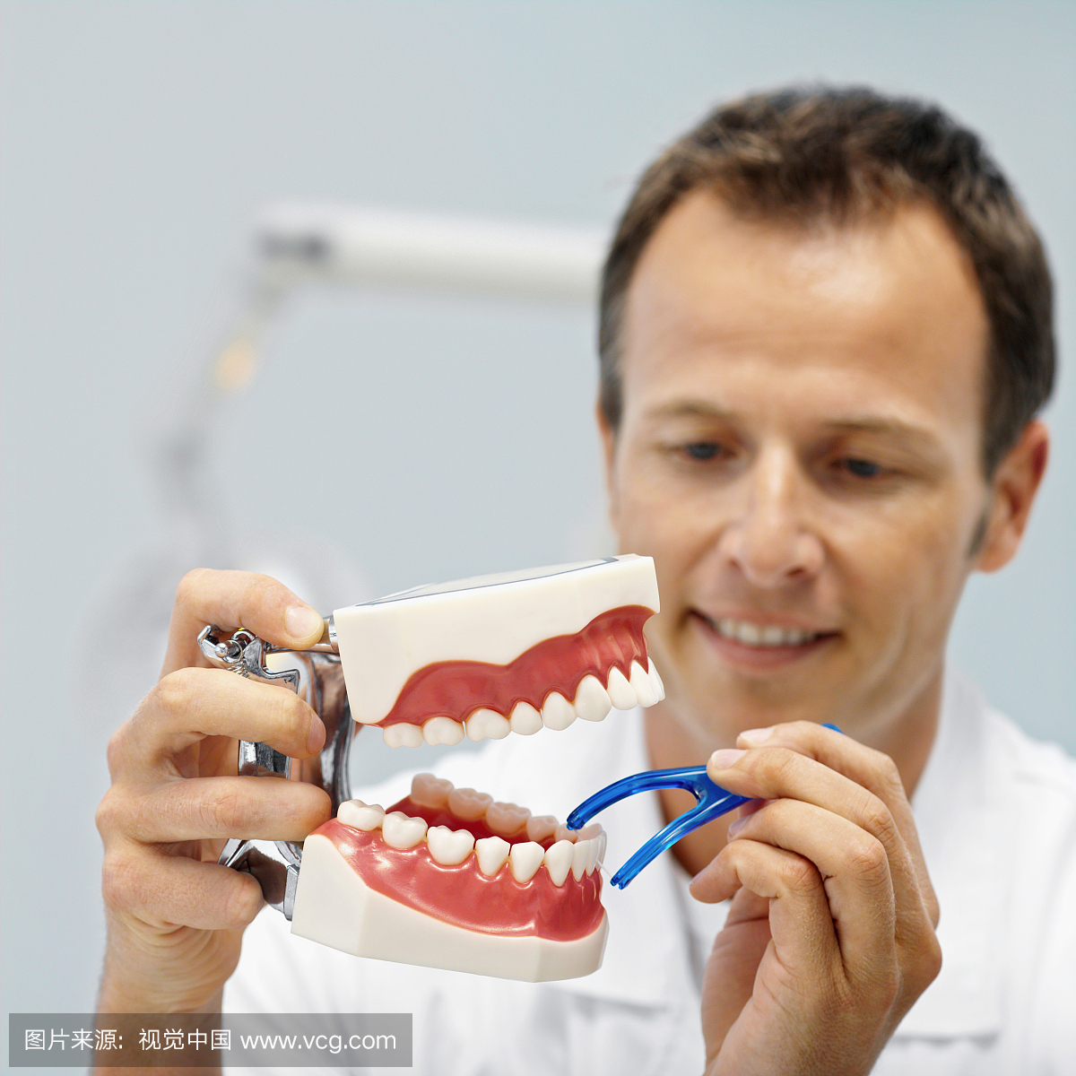 牙医的正面图像显示如何用牙线牙线牙线