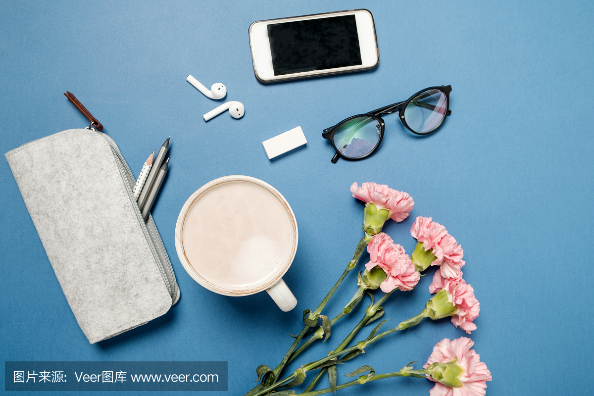 杯咖啡和粉红色康乃馨鲜花,电话和文具在蓝色