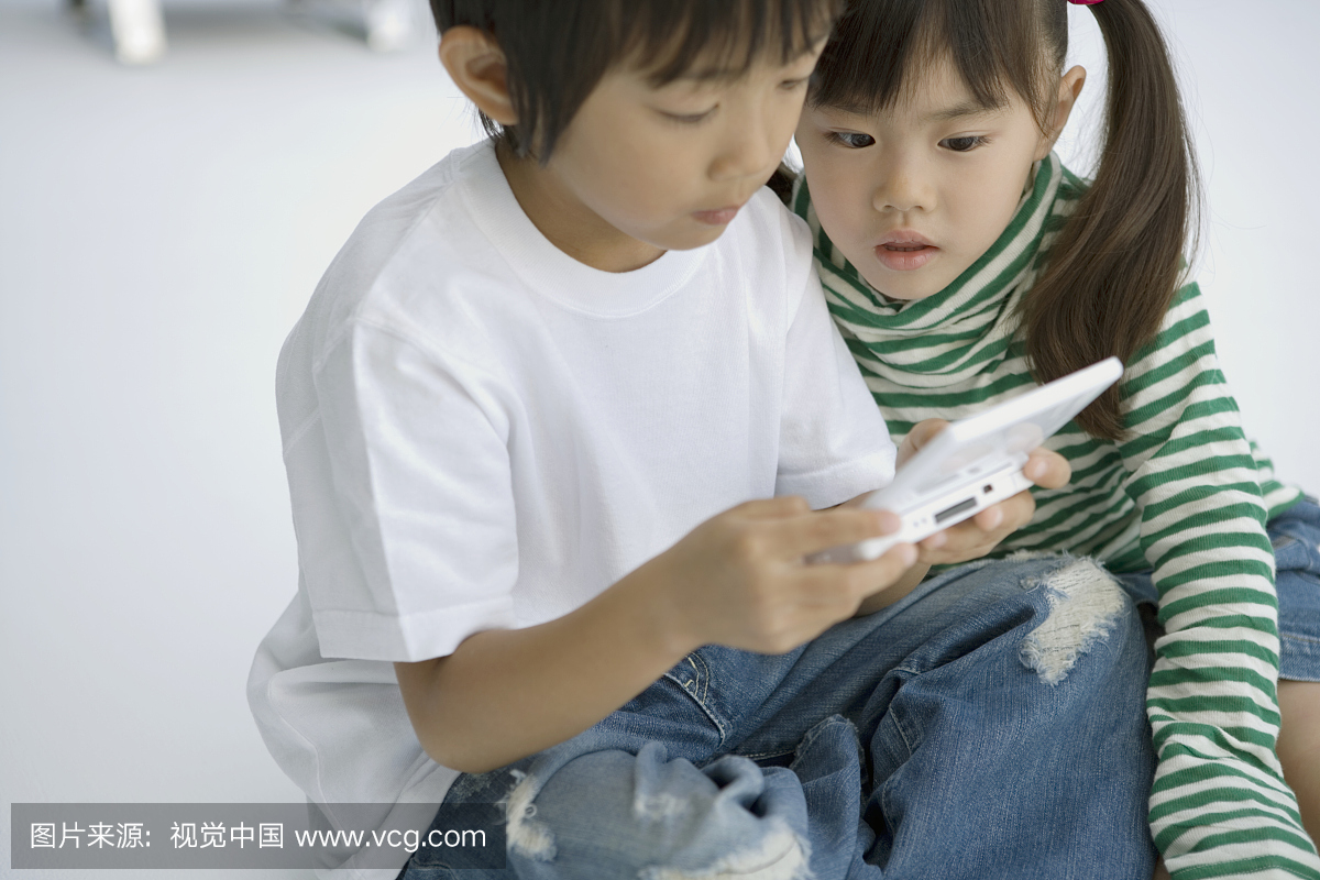 男孩(4-6岁)和女孩(3-5岁)坐在地板上玩电子游戏