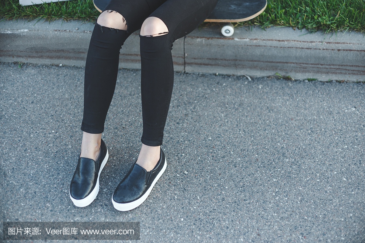 牛仔裤的年轻女子,下一步坐在地上的运动鞋
