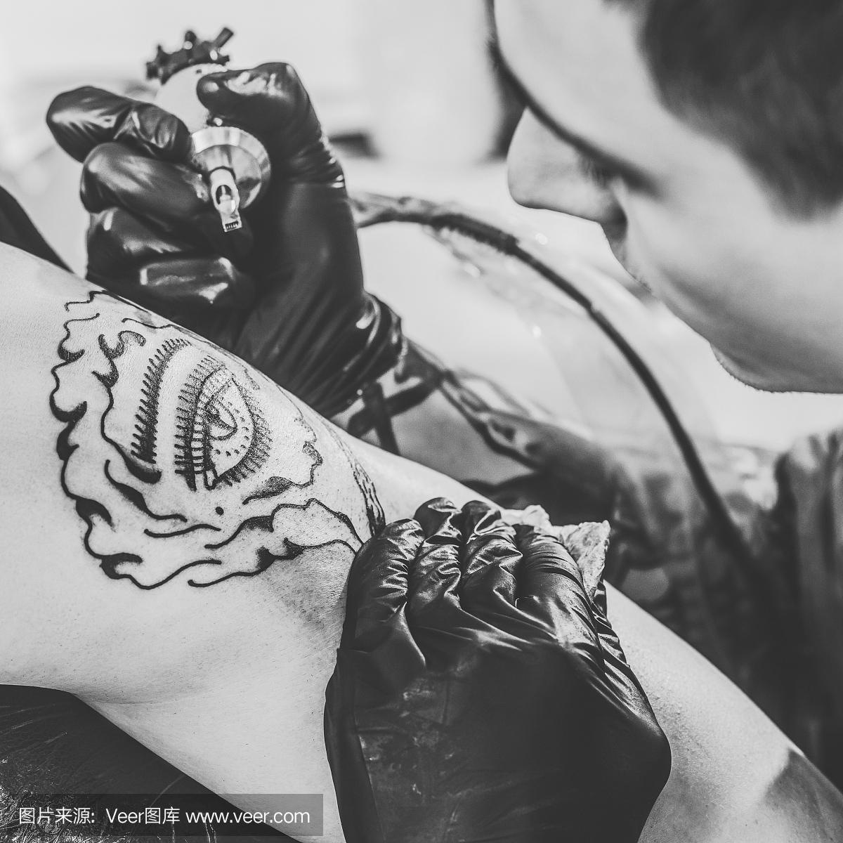 纹身艺术家在手套工作在肩膀片在工作室的黑白