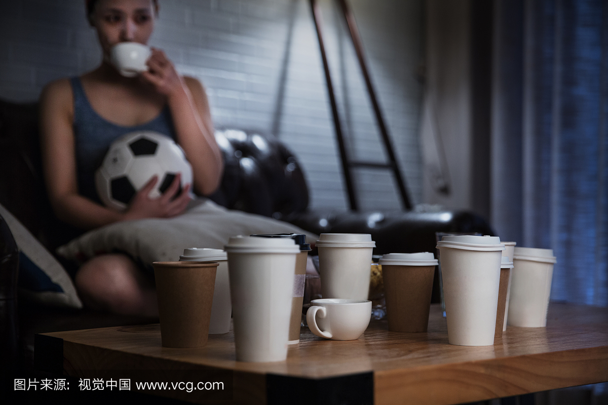 年轻女士喝咖啡熬夜看足球静物特写