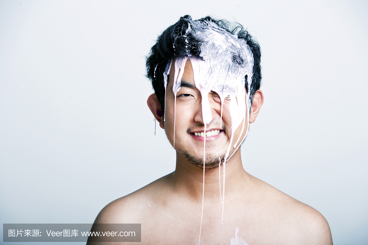 赤裸裸的年轻人,粉红色的油漆落在他的头上