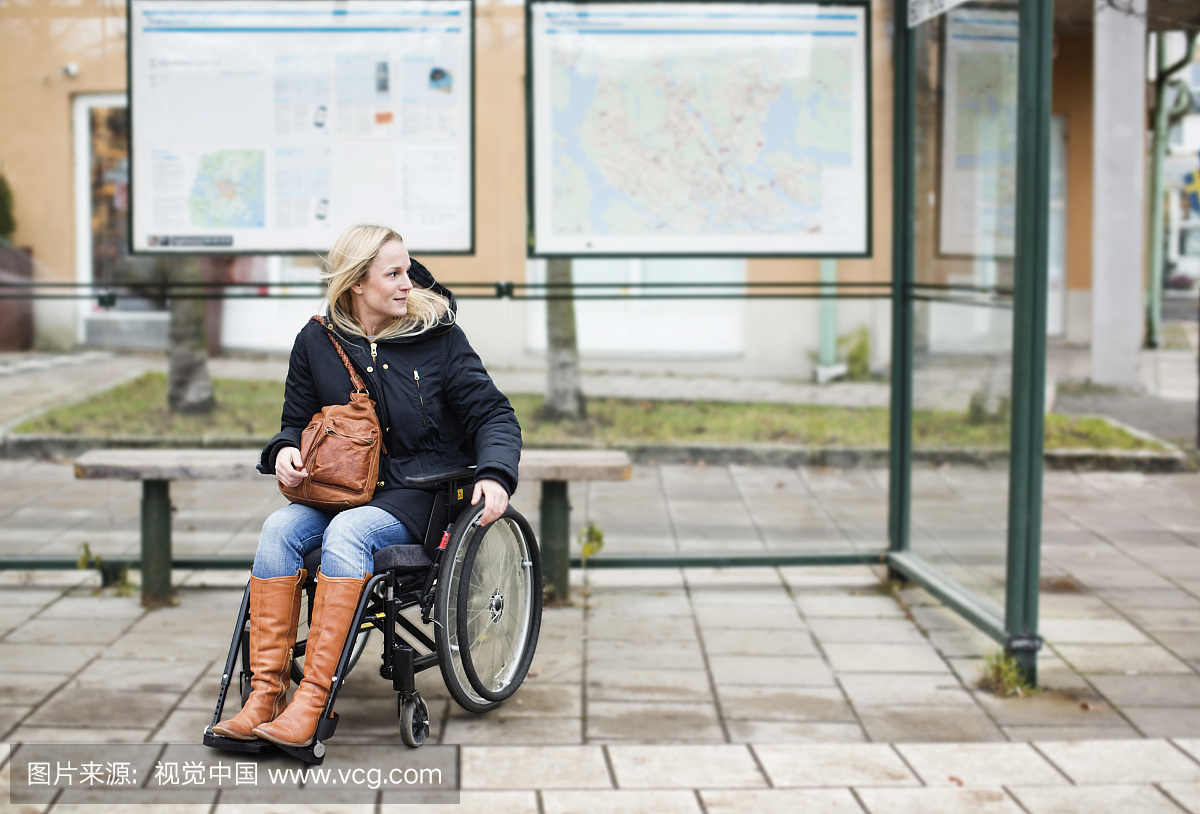 残疾妇女在轮椅上等候在公共汽车站
