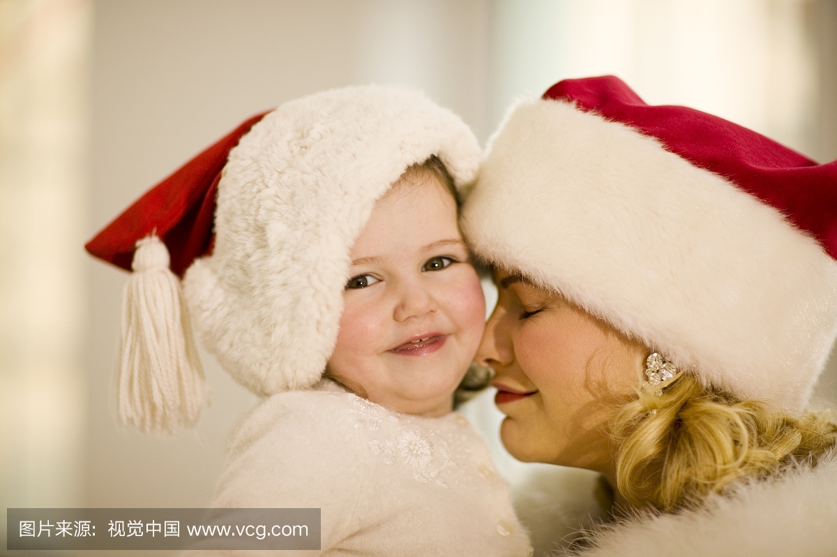 母亲和小女儿戴着圣诞老人的帽子
