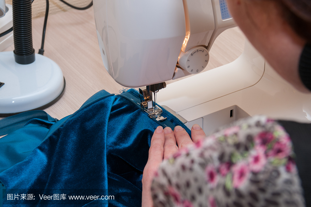 女人在缝纫机上缝上裙子