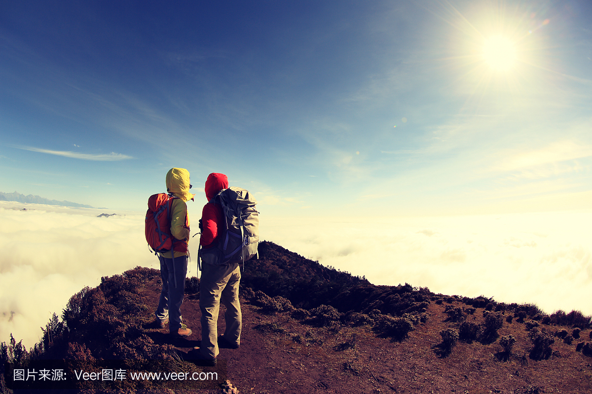两个成功的徒步旅行者在美丽的滚动云山峰