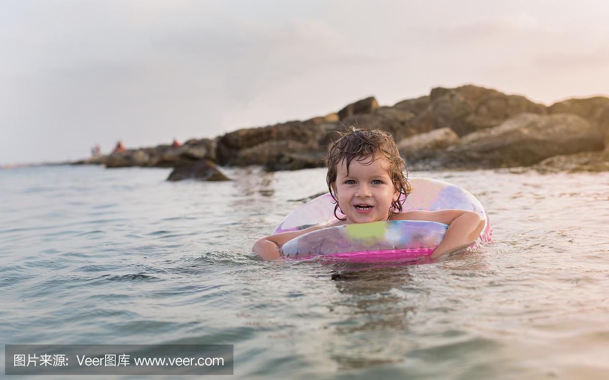 可爱的微笑的孩子在海边的一个游泳管。