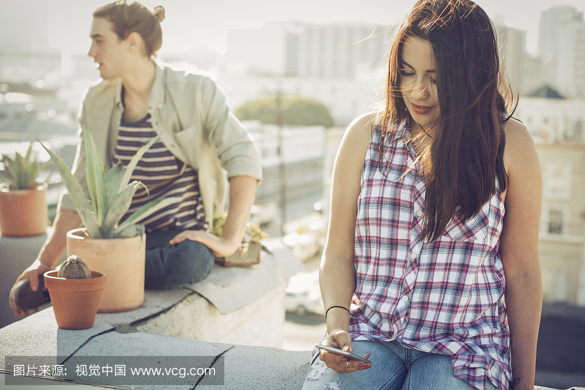 女性在城市屋顶上检查智能手机