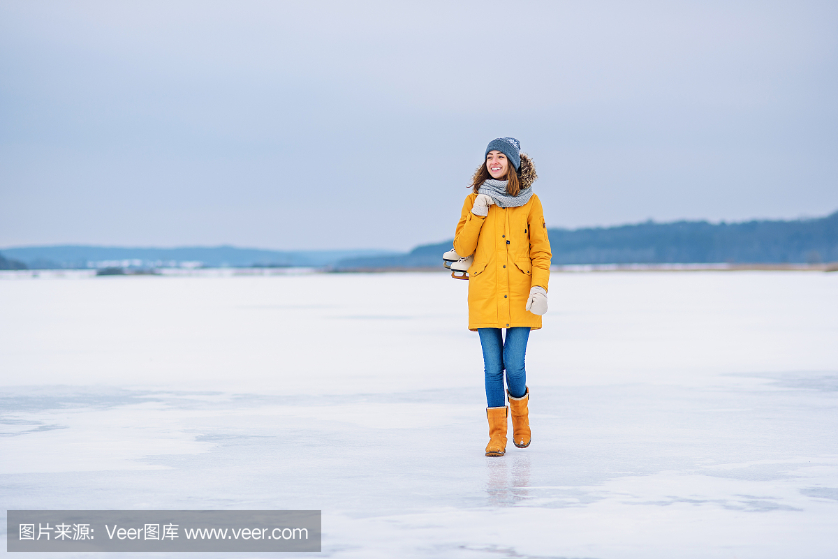 一件黄色外套,温暖的帽子和溜冰鞋在一个结冰