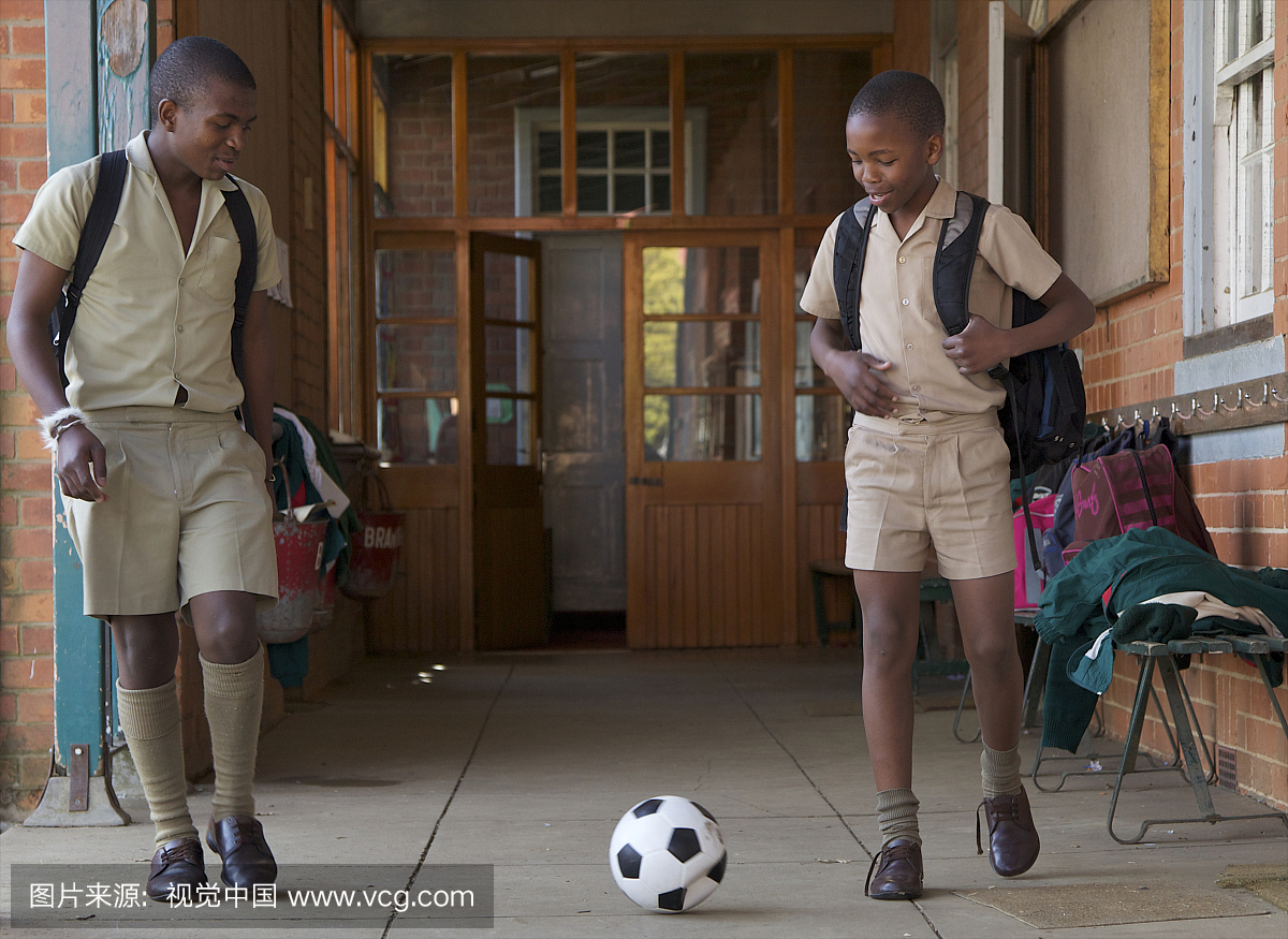 两名男子在南非夸祖鲁纳塔尔省教室外踢足球
