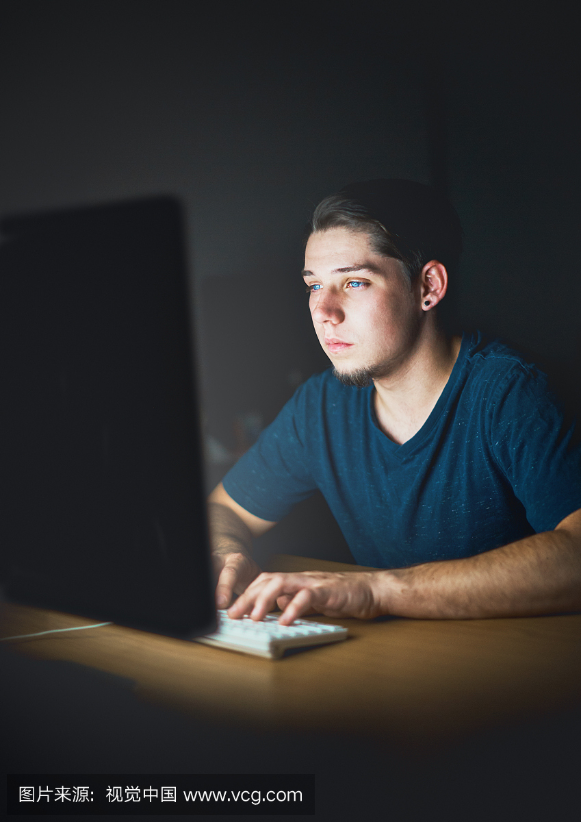 孤独的年轻人晚上在计算机上工作