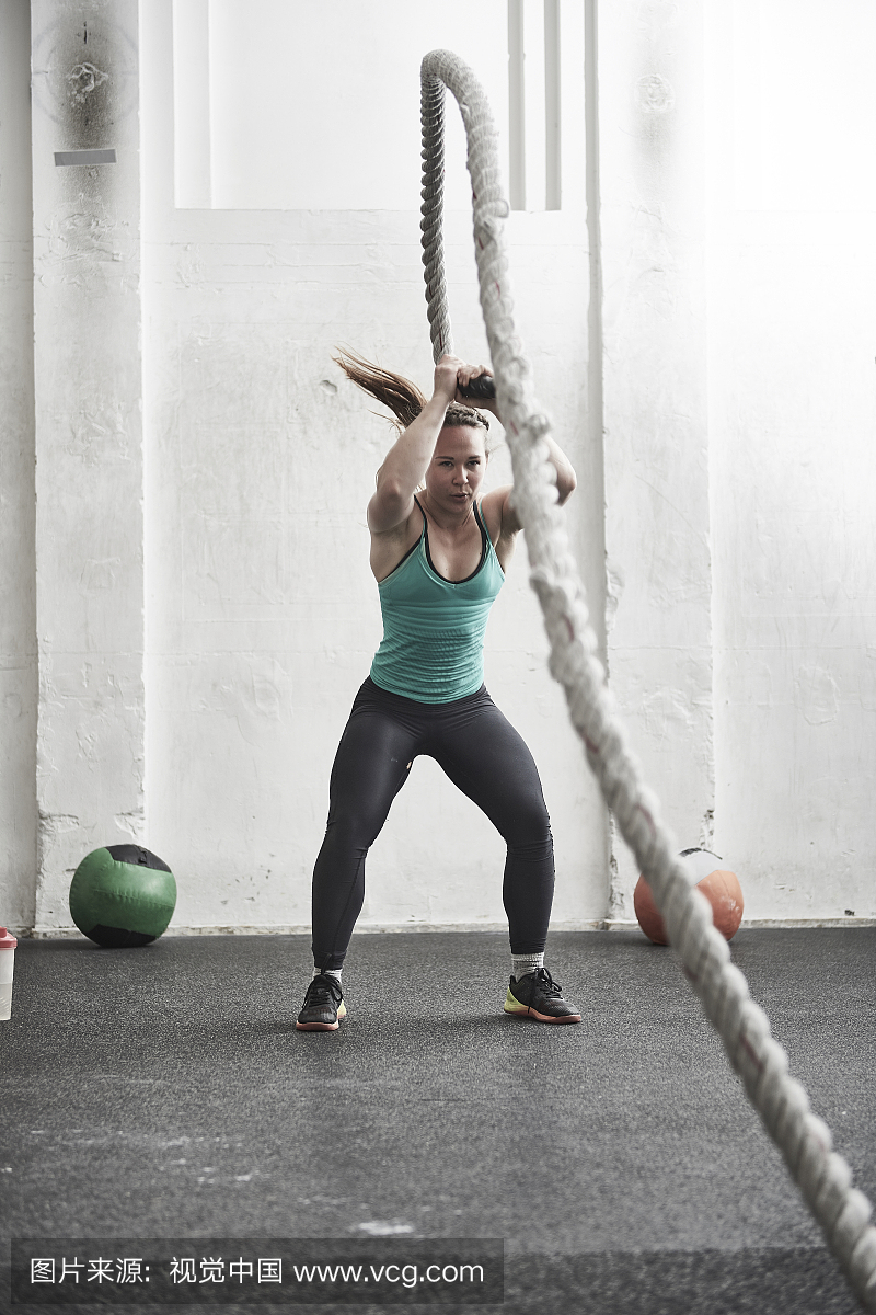 女人与战斗绳子在交叉训练健身房锻炼