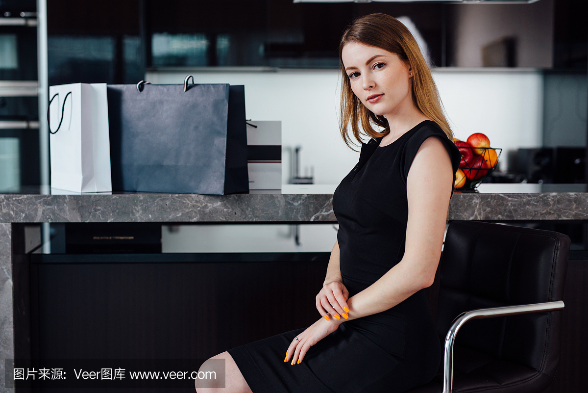 金发优雅女人穿着黑色连衣裙和高跟鞋坐在酒吧