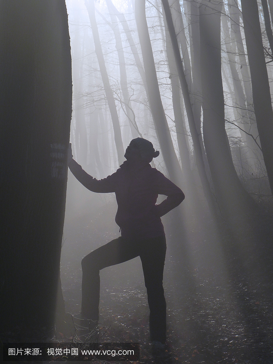 在雾天气中站在森林里的全长女人
