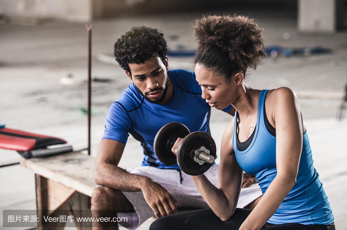 年轻女子举重与个人教练在她旁边