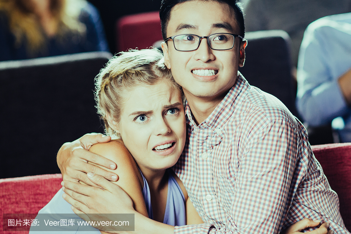 害怕的年轻夫妇在电影院观看恐怖片