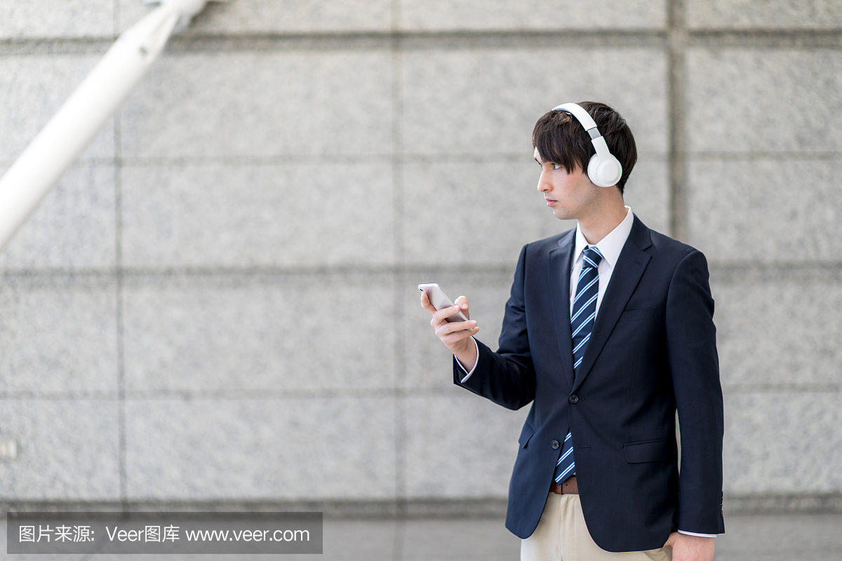 戴着无线耳机的年轻人,用智能手机听音乐